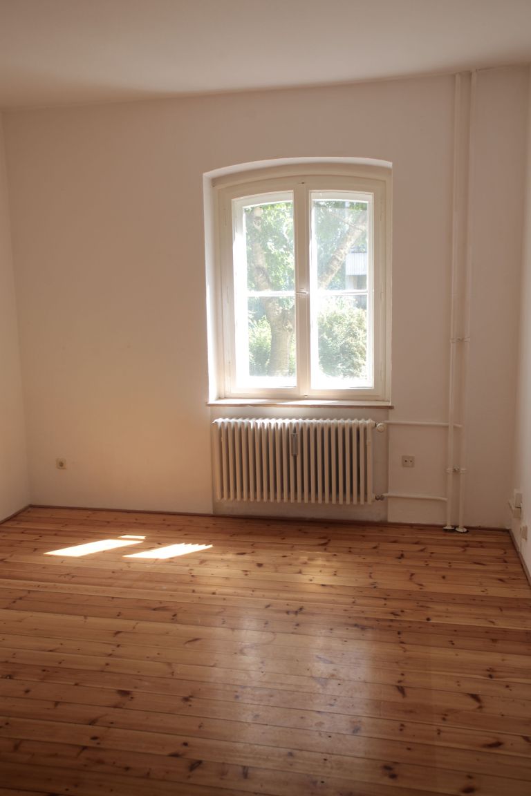 Leerer Raum mit verlegtem Holzboden, der bis an die Wand unter dem Fenster läuft